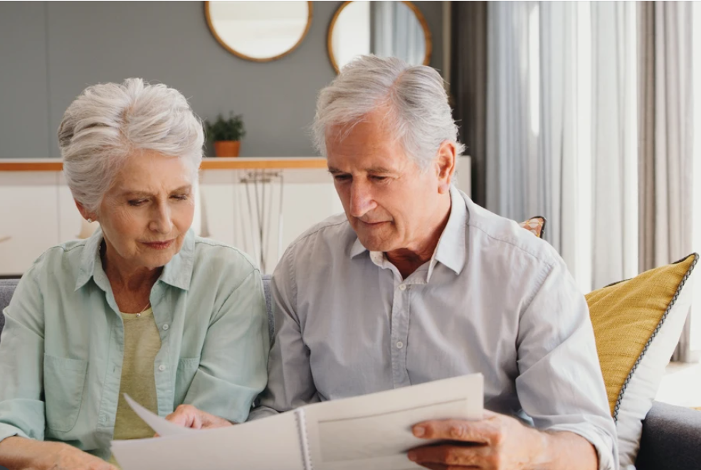 Older couple look at documents sat on sofa