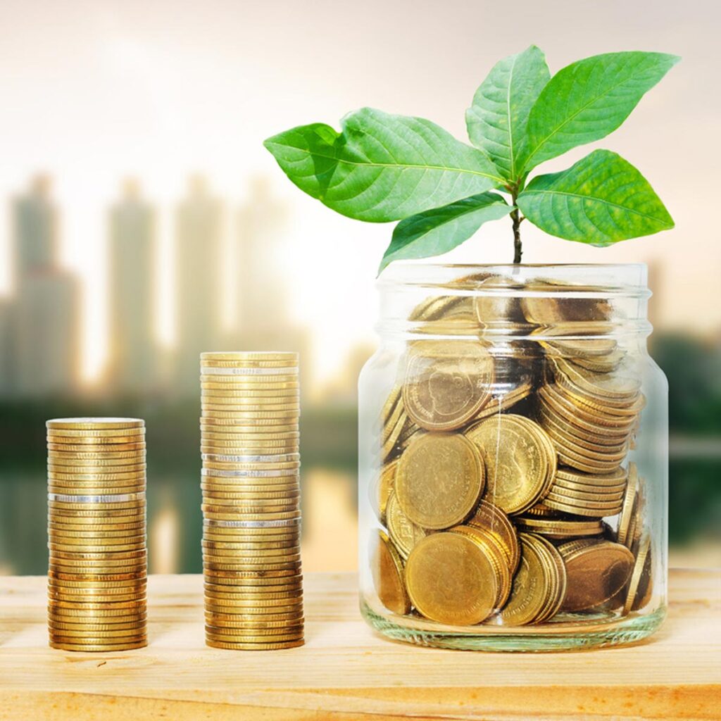 Green plant growing on golden coin in glass jar on wood table with morning blur cityscape background. business financial banking saving concept. investment profit income. marketing startup success.