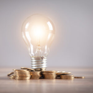 Light bulb and stack of coins on the desk. Saving energy and money