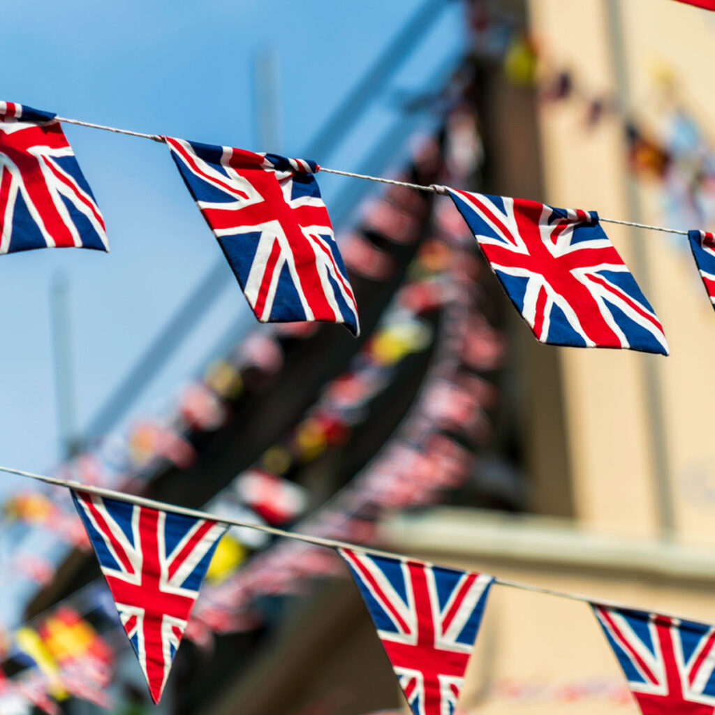 Multiple British flags waving, flying make for a festive background. The national UK flags are a British icon and part of the British, English culture. The Union Jack flags decorate city streets and are hung in squares across cities in the UK for celebrations and to show pride, patriotism.