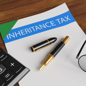 Inheritance Tax headed paper and pen on desk with calculator and spectacles