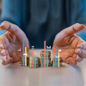 Hands around coins and a virtual chart